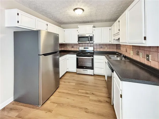 a kitchen with granite countertop a refrigerator stove and sink