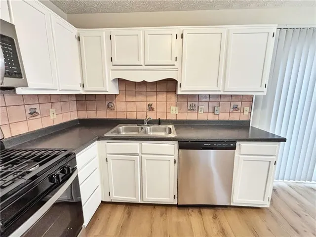 a kitchen with stainless steel appliances a white stove top oven sink and cabinets