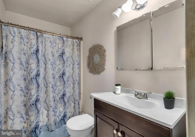 a bathroom with a sink a toilet and shower curtain