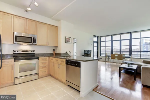 a kitchen with stainless steel appliances granite countertop a stove top oven a sink a dining table and chairs
