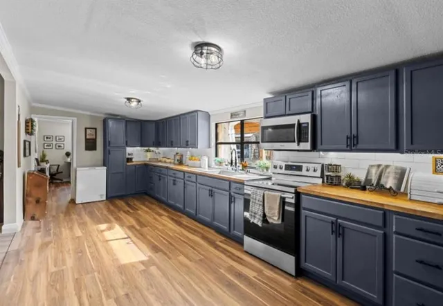 a large kitchen with stainless steel appliances granite countertop a sink dishwasher stove and wooden cabinets