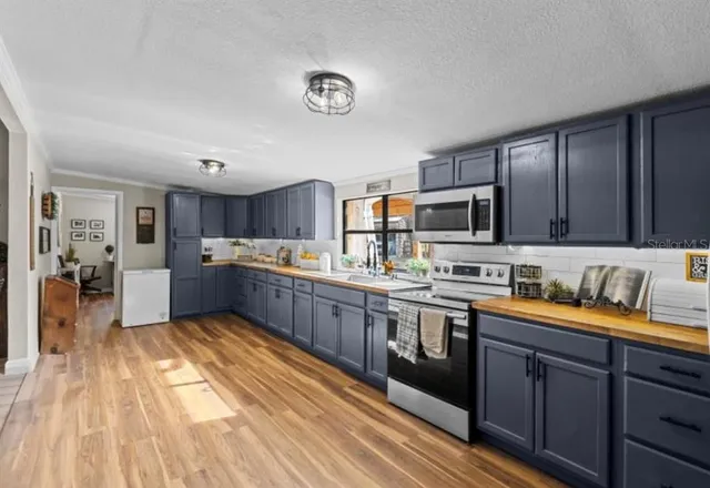 a large kitchen with stainless steel appliances granite countertop a sink dishwasher stove and wooden cabinets