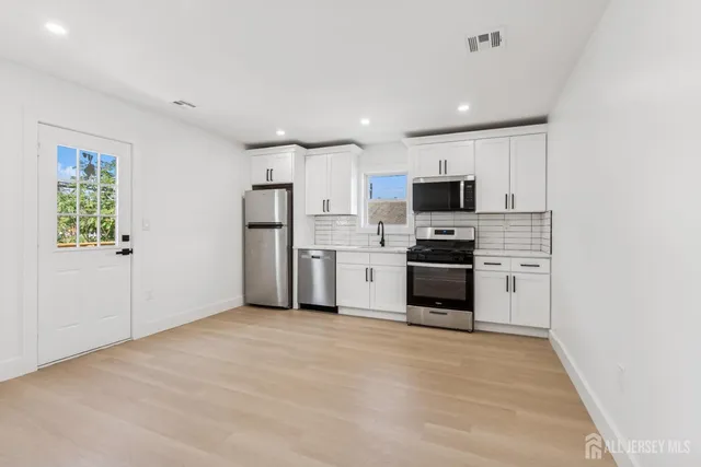 a kitchen with granite countertop a refrigerator and a stove top oven