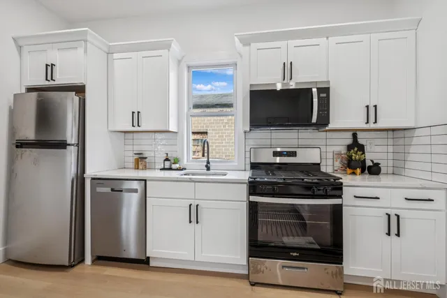 a kitchen with white cabinets stainless steel appliances and sink