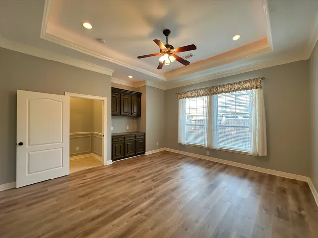 a view of an empty room with a window and wooden floor