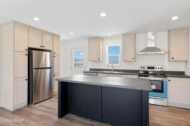 a kitchen with stainless steel appliances granite countertop a sink a stove a refrigerator and white cabinets