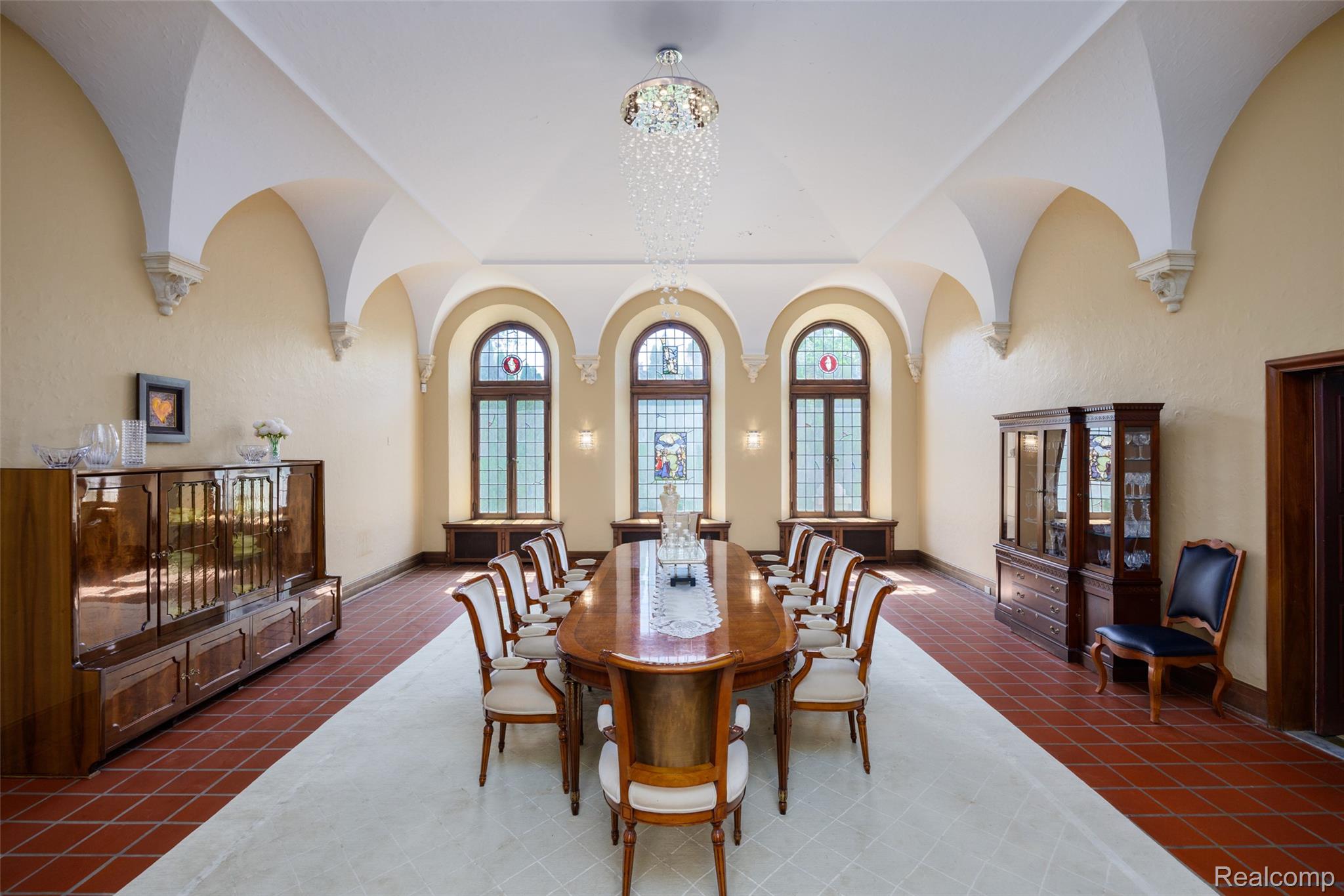 189 Cloverly Road Grosse Pointe, MI 48236 - Photo 15 of 93 A room created to celebrate the occasion. Illuminated by three magnificent leaded-glass windows, the formal dining room is crowned by a soaring barrel-vaulted ceiling supported by graceful arches and hand-carved corbels. Designed for everything from intimate family dinners to elegant holiday celebrations, it reflects the home’s enduring tradition of gracious hospitality. The formal Dining Hall is perfectly positioned between the atrium and reception spaces, creating a memorable setting for elegant dinners, celebrations, and holiday gatherings.