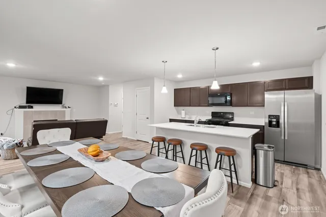 a kitchen with a dining table chairs refrigerator and microwave
