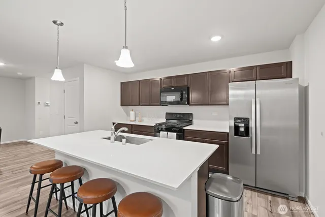 a kitchen with stainless steel appliances a dining table chairs and wooden floor