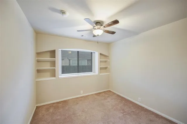 an empty room with a window and a fan