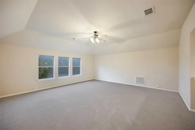 an empty room with chandelier fan and windows