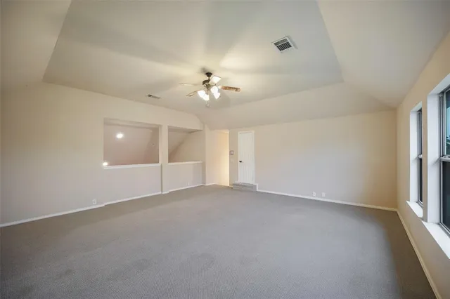 an empty room with chandelier fan and windows