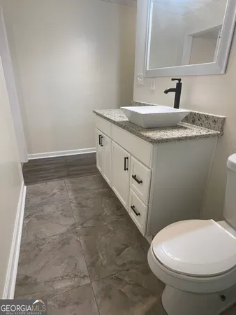 a bathroom with a granite countertop sink a toilet and a mirror