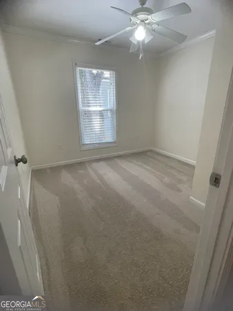 an empty room with a chandelier fan and windows
