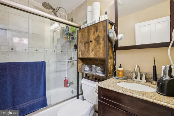 a bathroom with a granite countertop sink a toilet and shower