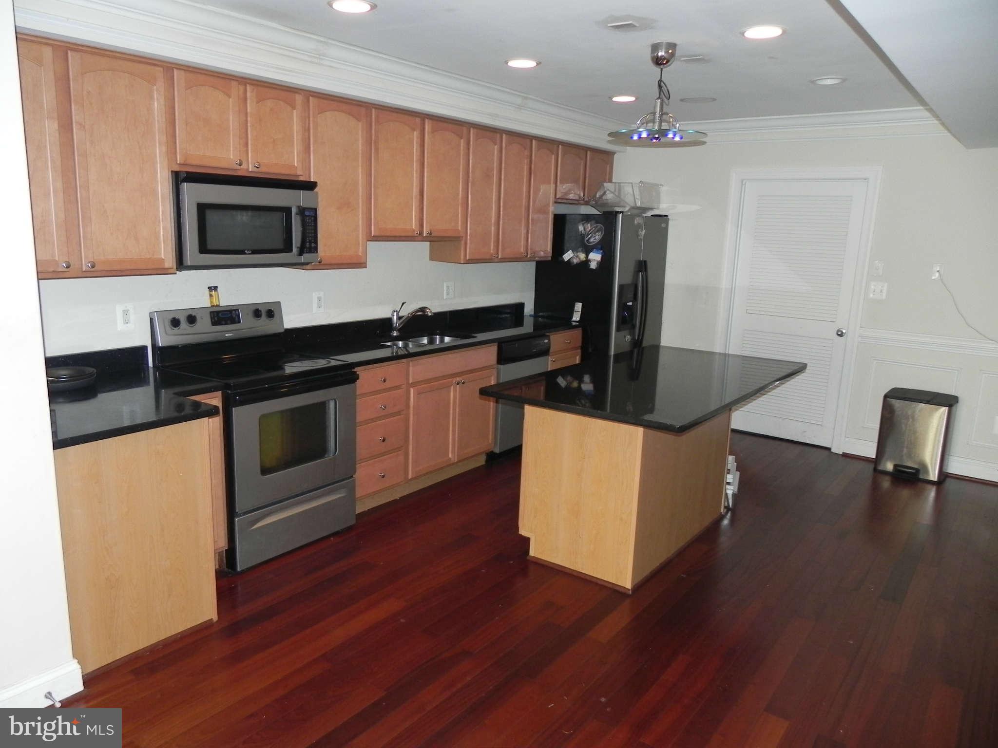 106 West Cross Street Baltimore, MD 21230 - Photo 7 of 29 a kitchen with granite countertop a stove top oven a sink dishwasher a refrigerator and a dining table with wooden floor