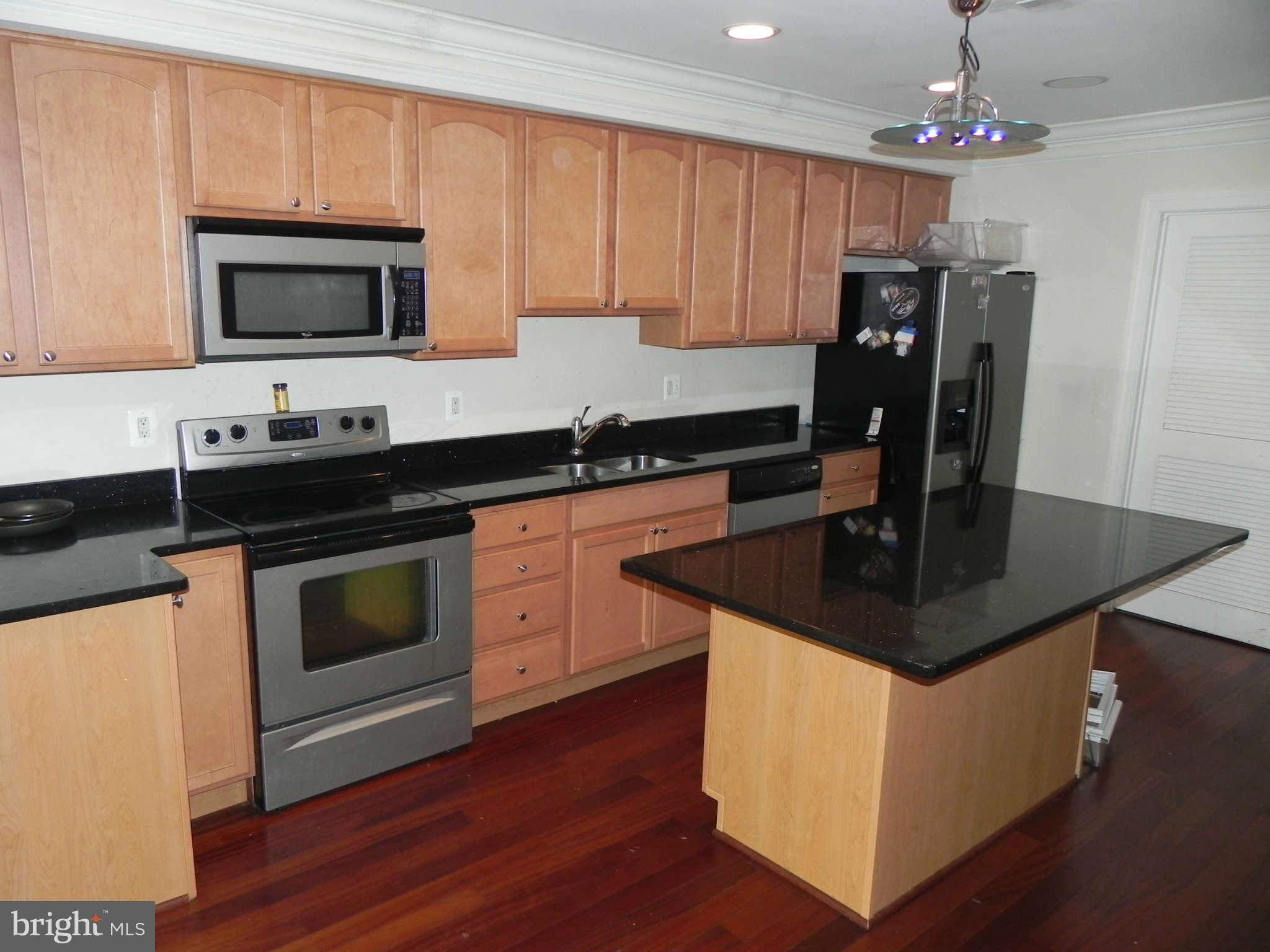 106 West Cross Street Baltimore, MD 21230 - Photo 8 of 29 a kitchen with kitchen island granite countertop a sink cabinets and stainless steel appliances