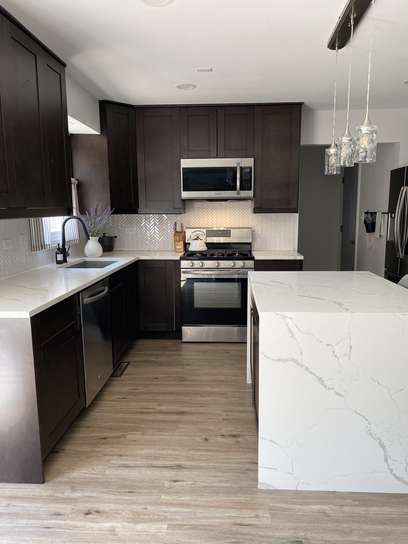 1900 Eagle Circle New Lenox, IL 60451 - Photo 4 of 16 a kitchen with stainless steel appliances granite countertop a sink a stove top oven and wooden floors