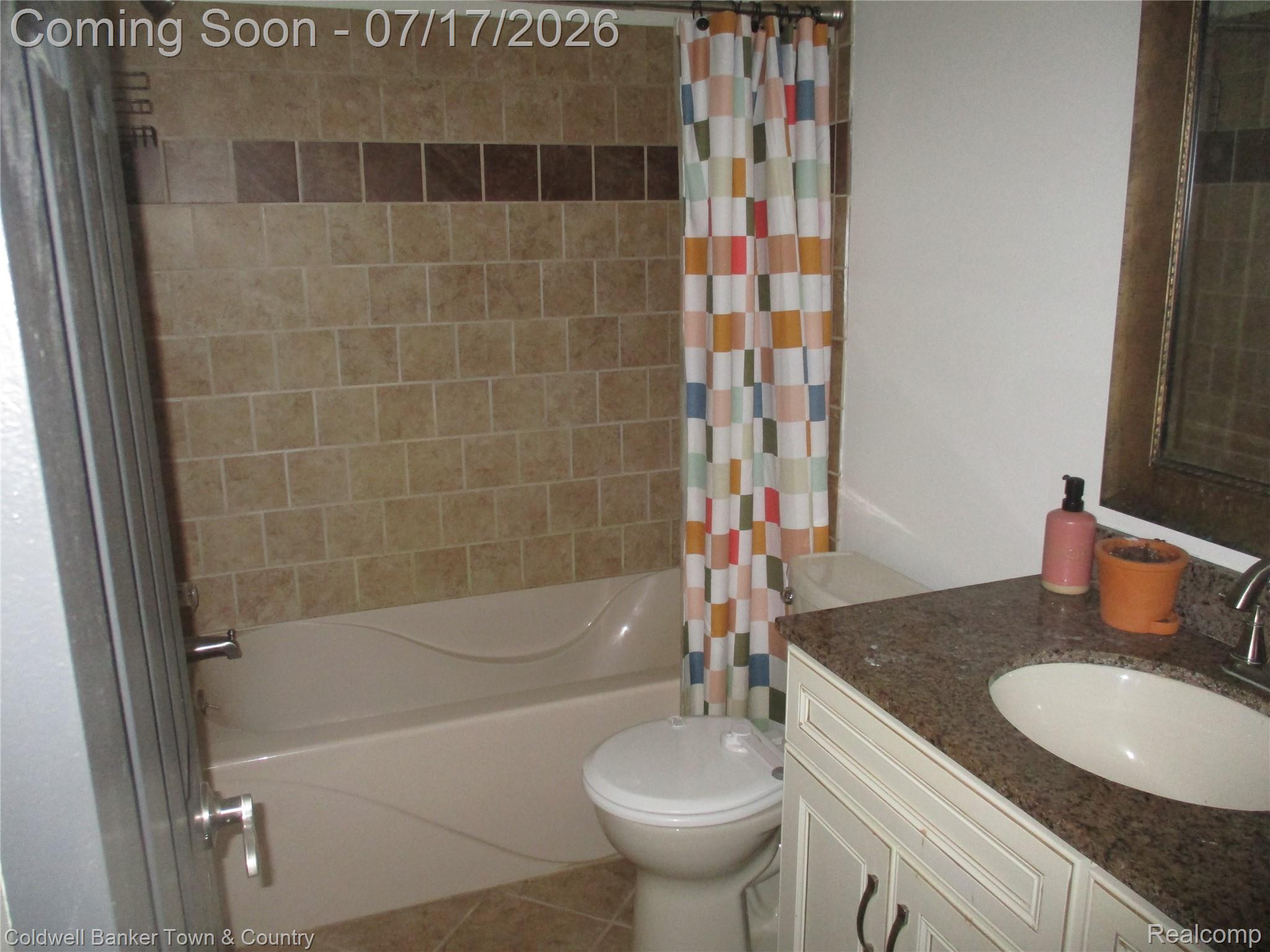 1996 Triangle Lake Road Howell, MI 48843 - Photo 10 of 32 Bathroom featuring floor-to-ceiling tiled shower surround with accent band, integrated bathtub, and a vanity with an undermount sink and stone countertop