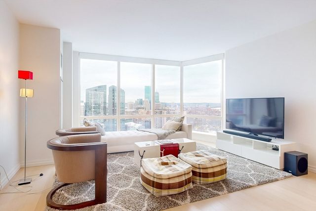 a living room with furniture a flat screen tv and a large window