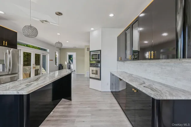 a large kitchen with stainless steel appliances granite countertop plenty wooden cabinets counter space and wooden floor