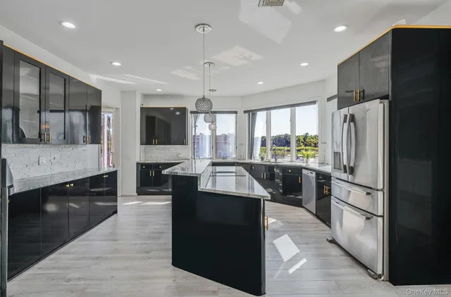 a large kitchen with stainless steel appliances kitchen island granite countertop a refrigerator and a stove top oven