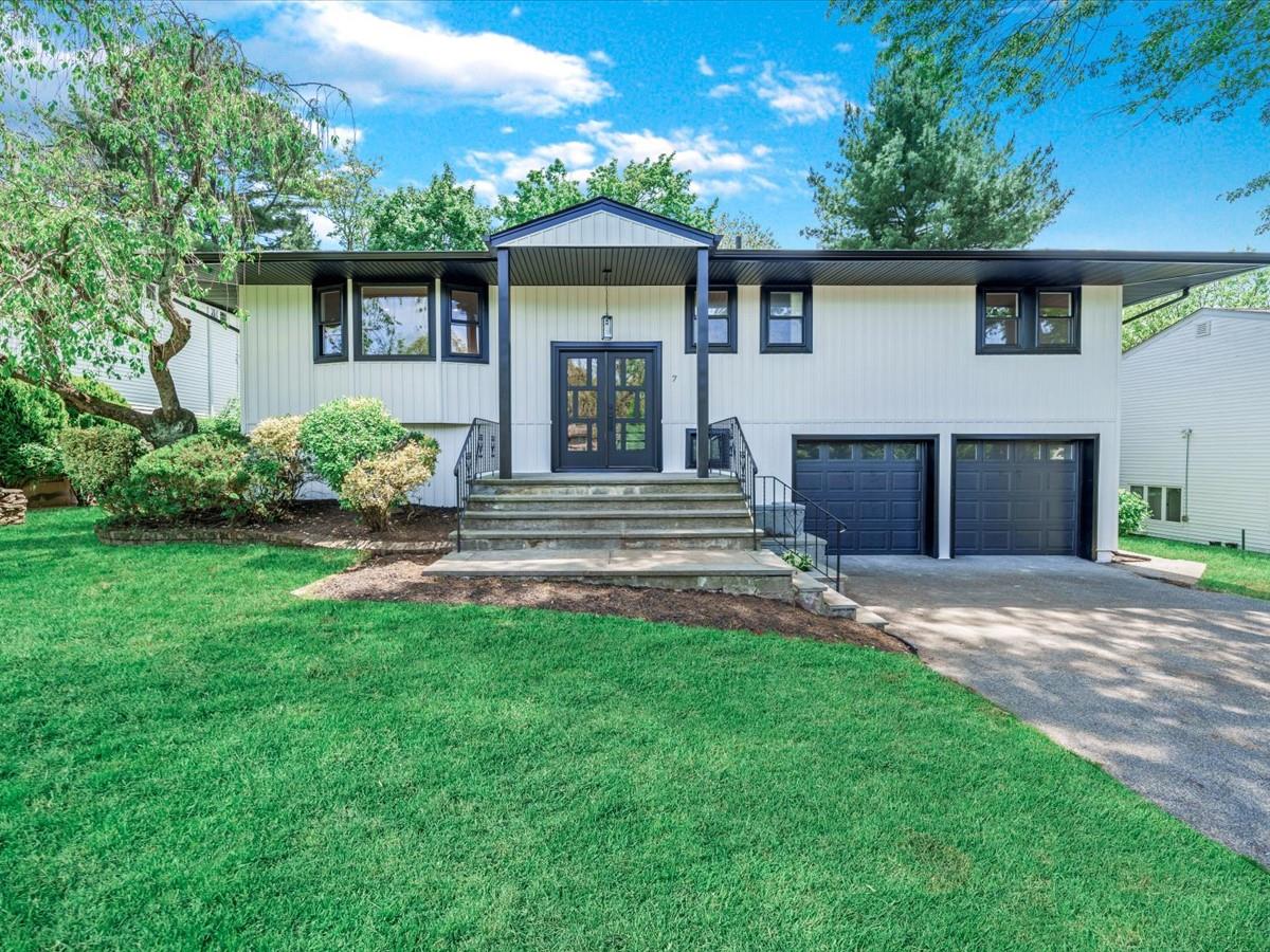 Raised ranch with french doors, an attached garage, asphalt driveway, and a front lawn