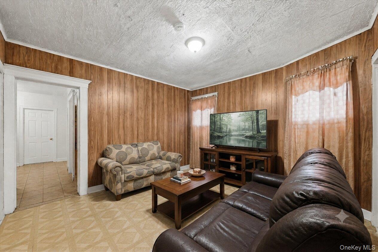 34 Spring Street Middletown, NY 10940 - Photo 7 of 33 Virtually Decluttered. Spacious living room with wood-paneled walls, multiple windows, and a flexible layout.