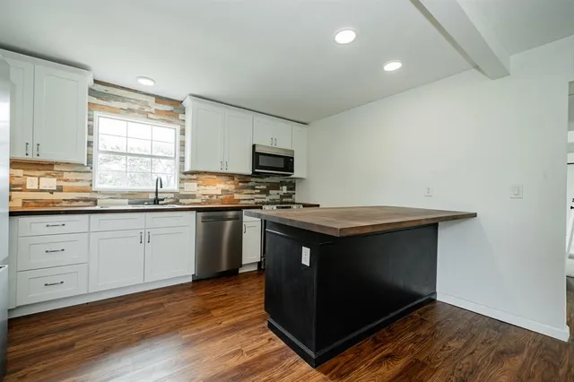 a kitchen with stainless steel appliances granite countertop a stove a sink and a microwave