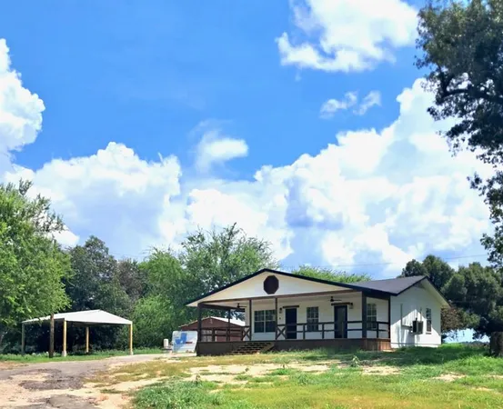 a white house with a big yard and large trees