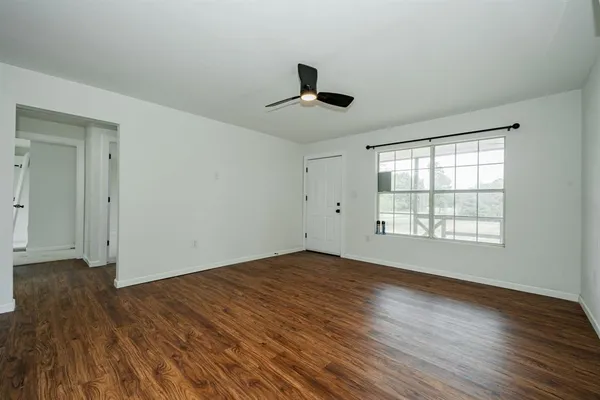 a view of an empty room with wooden floor and a window