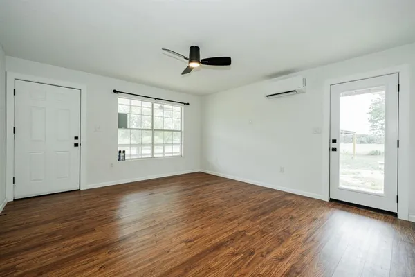 a view of an empty room with wooden floor and a window