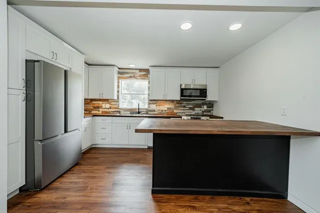 a kitchen with kitchen island granite countertop stainless steel appliances and wooden cabinets