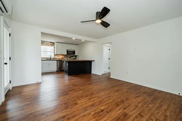 a view of kitchen and empty room with wooden floor