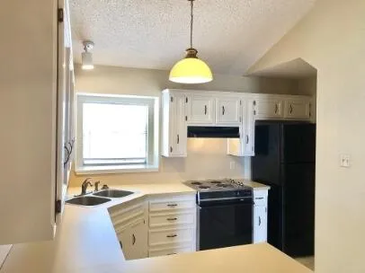 a kitchen with granite countertop a stove a sink and a refrigerator