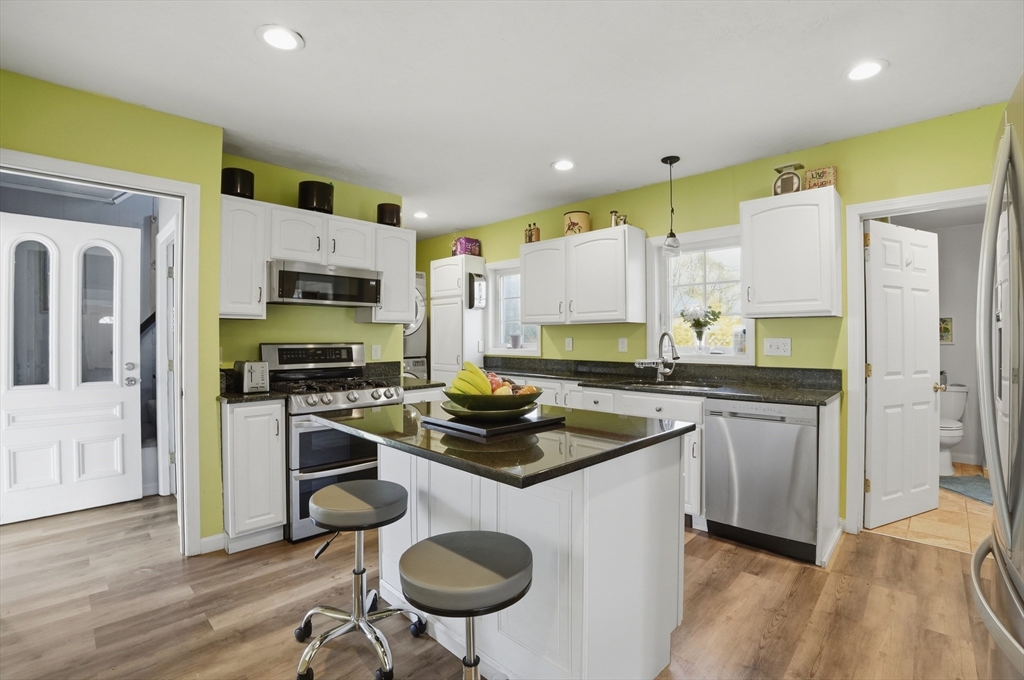 59 Cottage Street Franklin, MA 02038 - Photo 12 of 42 a kitchen with stainless steel appliances granite countertop a sink a stove a refrigerator a microwave oven with white cabinets and wooden floor