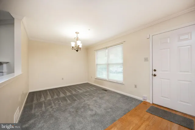 an empty room with chandelier fan and windows