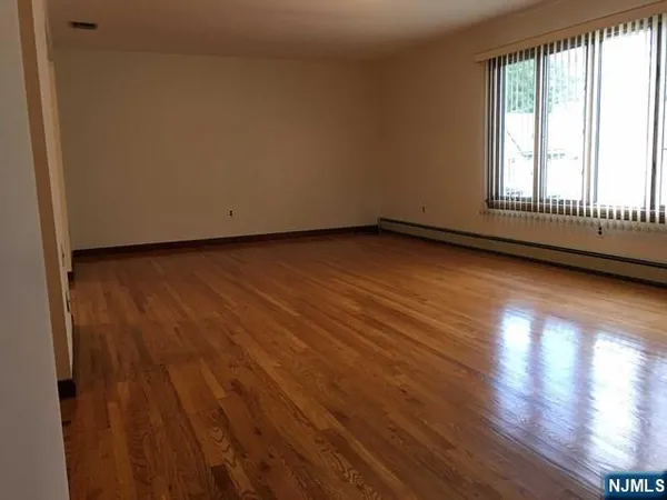 a view of an empty room and wooden floor and window