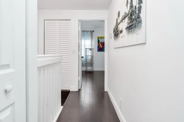 a view of a hallway with wooden floor and closet