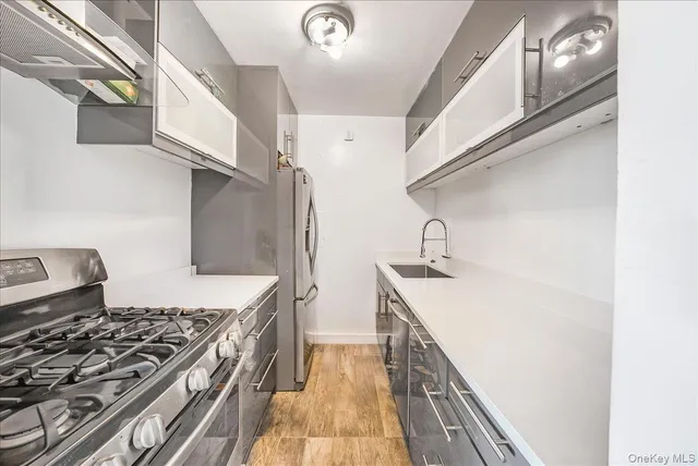 a view of a hallway with wooden floor and a bathroom