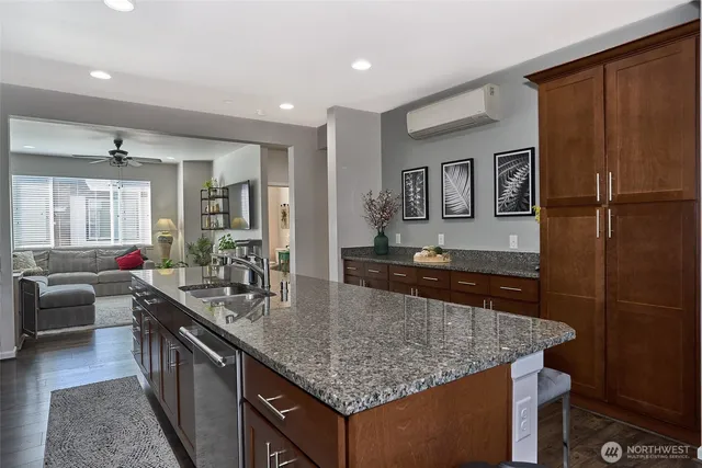 a kitchen with granite countertop a sink and dishwasher a refrigerator with wooden cabinets