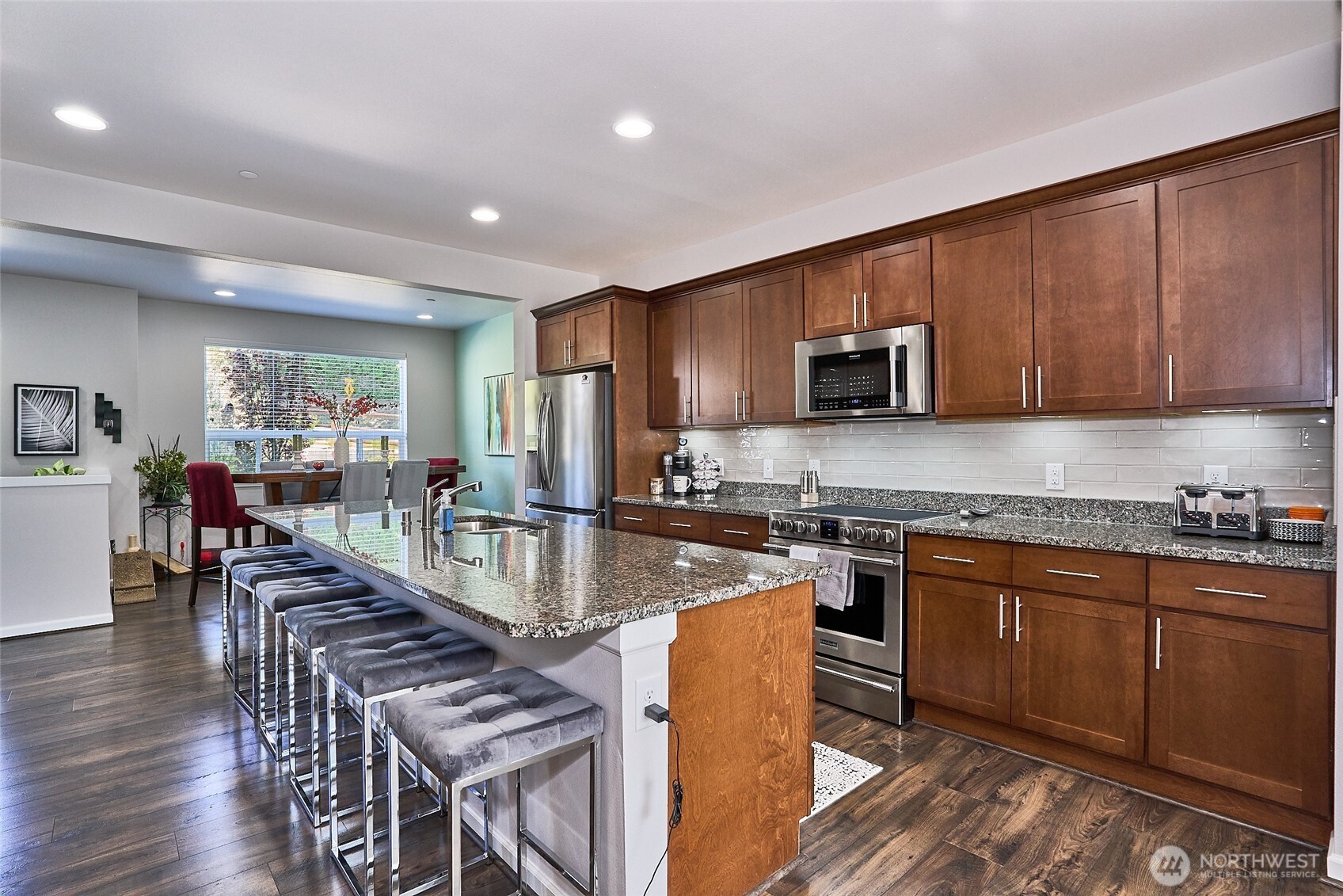 13146 83rd Lane South Seattle, WA 98178 - Photo 8 of 22 a kitchen with stainless steel appliances granite countertop a stove top oven a sink dishwasher a dining table and chairs with wooden floor