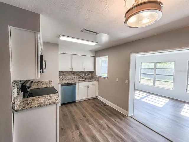 a kitchen with a stove a refrigerator and a wooden floor