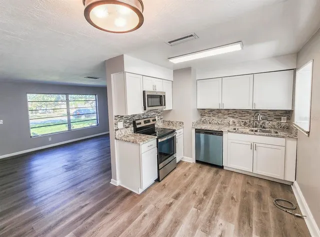 a kitchen with granite countertop white cabinets and white appliances