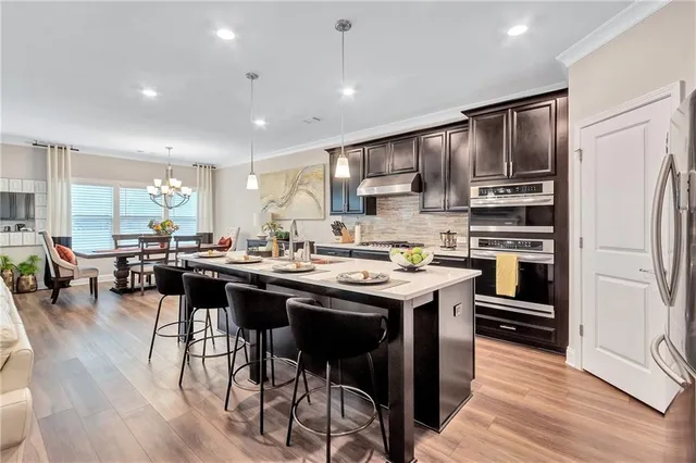a kitchen with stainless steel appliances granite countertop a table chairs refrigerator and sink
