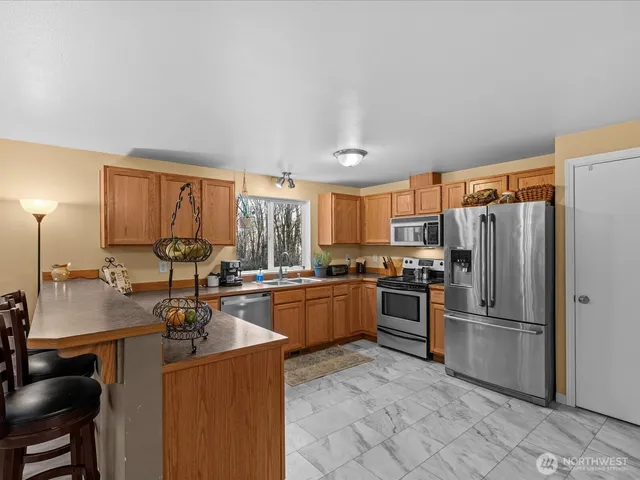 a kitchen with sink a stove and chairs with wooden floor