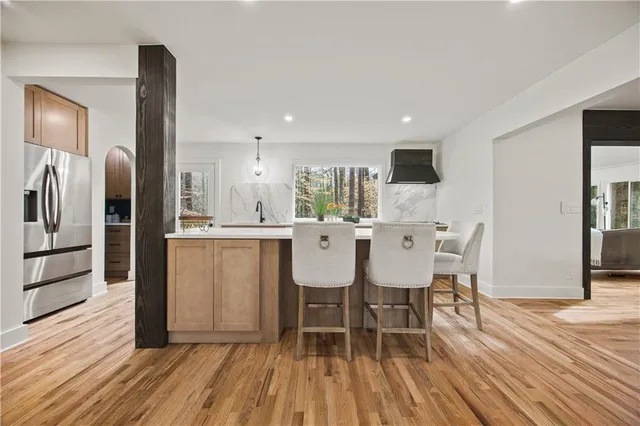 a kitchen with stainless steel appliances a dining table chairs refrigerator and sink