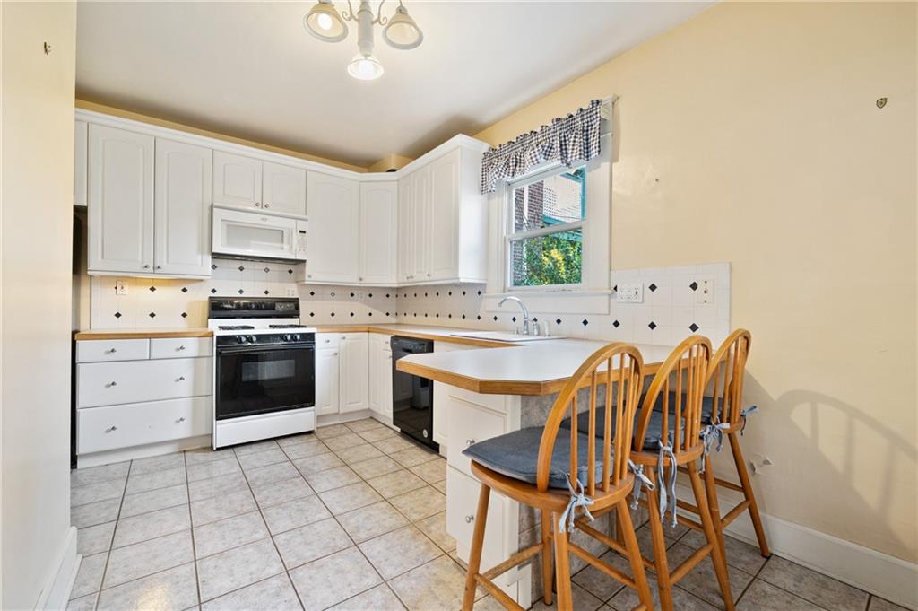514 Park Road Ambridge, PA 15003 - Photo 8 of 25 a kitchen with a stove a sink white cabinetry and chairs