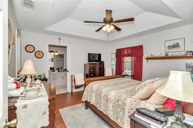 a bedroom with a bed and dresser with wooden floor