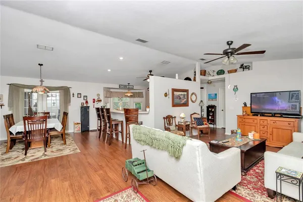 a living room with furniture kitchen view and a wooden floor